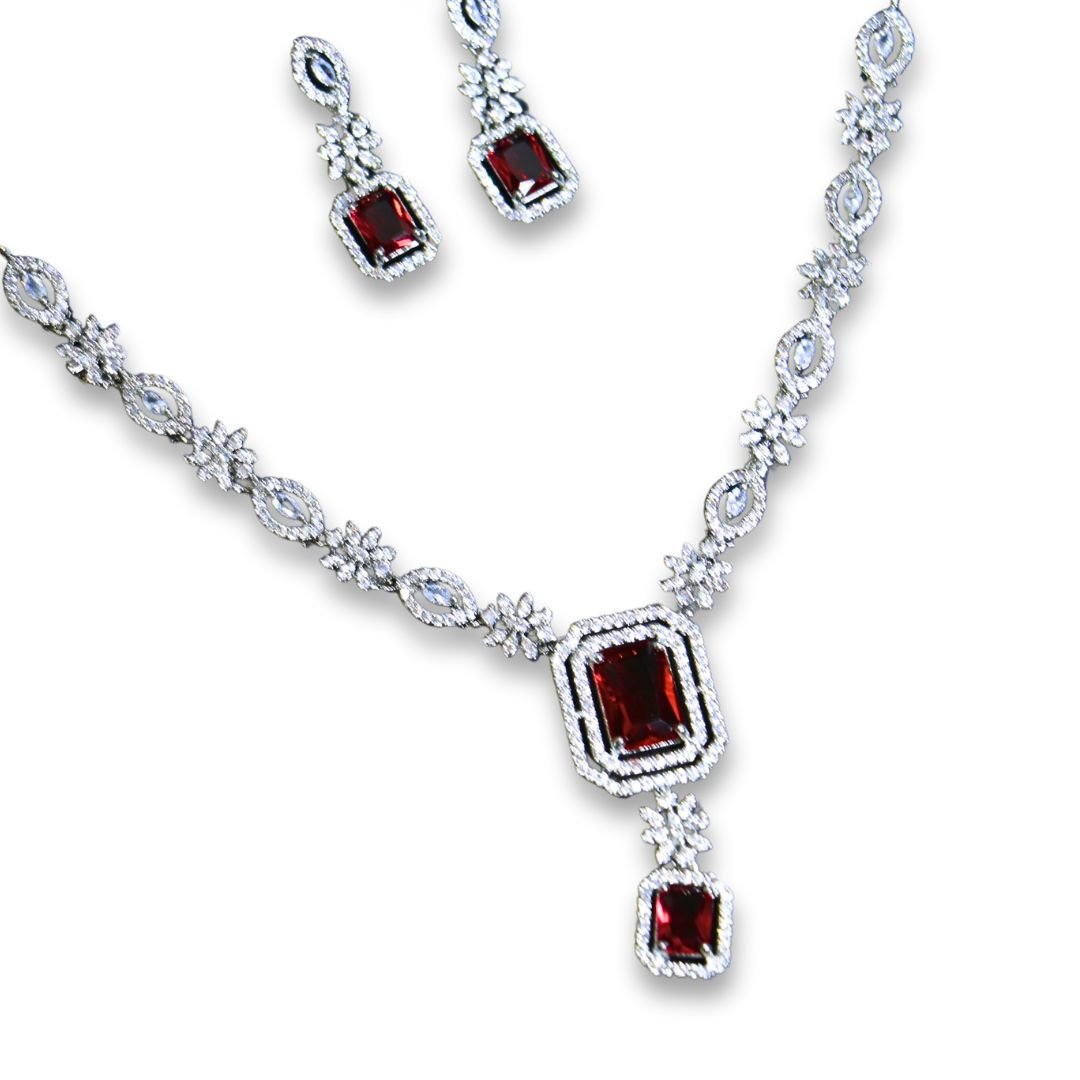 Elegant silver necklace and earring set with ruby red stones and diamond-like embellishments